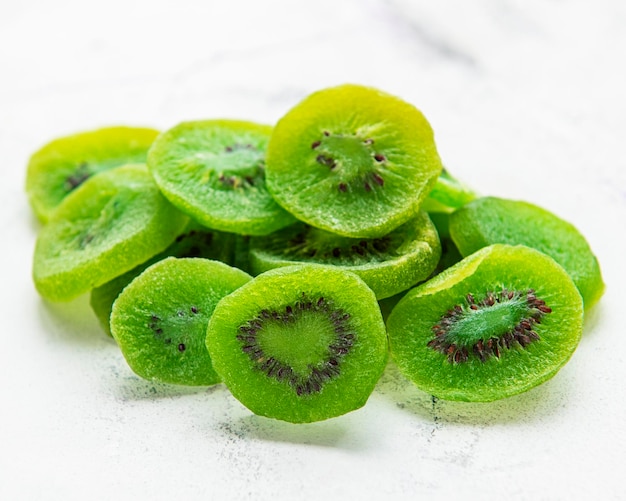 Pieces of dry kiwi  on a white marble background