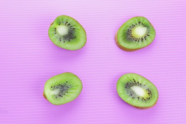 Pieces of fresh kiwi fruit on color background. Kiwi on purple background