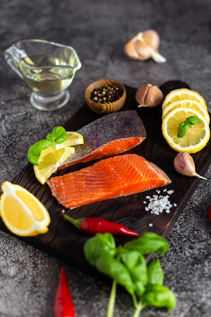 Pieces of fresh trout on a wooden board Herbs spices and lemon for cooking