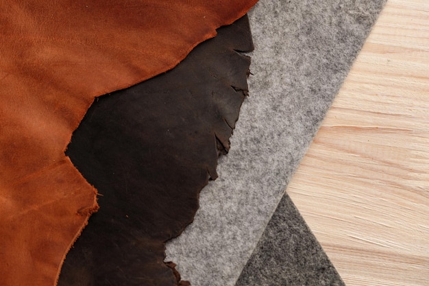 Pieces of genuine leather and felt on a wooden table Top view The concept of handmade leather goods Copy space