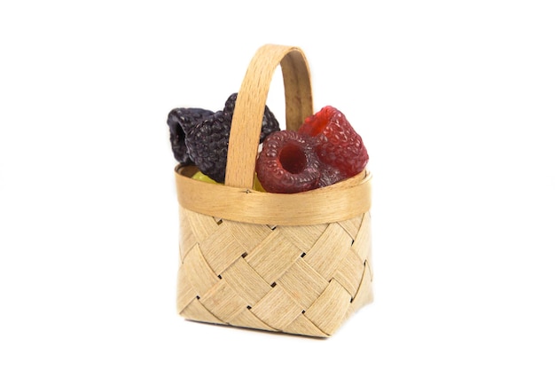 Pieces of handmade soap in the form of raspberries in a wooden basket on a white background