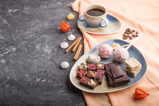 A pieces of homemade chocolate with coconut candies and a cup of coffee. side view