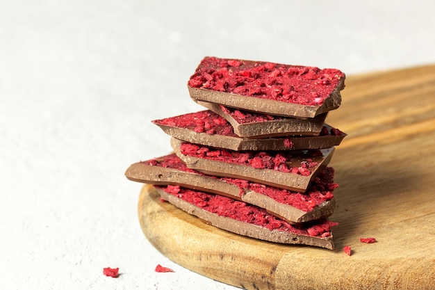 Pieces of milk chocolate with pieces of berries and fruits lie on top of each. Selective focus, place for text.