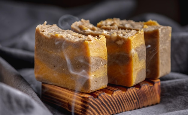 Pieces of natural handmade soap on a wooden soap dish and the dark background