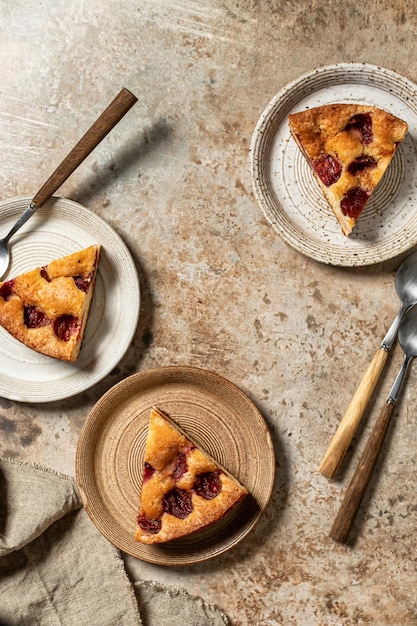 Pieces of The New York Times Plum Cake pie for three person on brown textured background top view