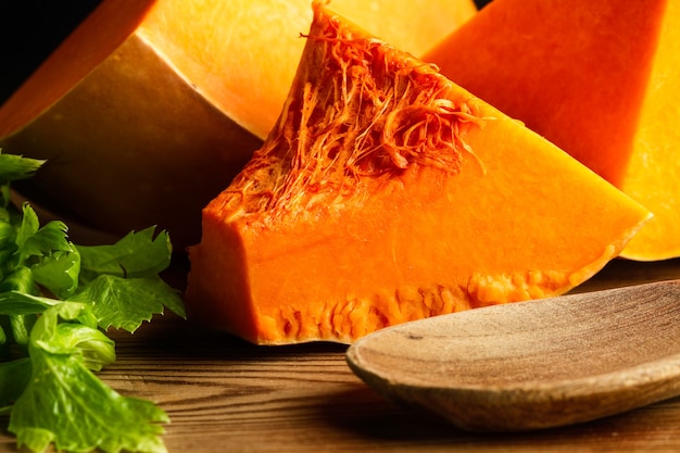 Pieces of pumpkin on a wooden table with a wooden spoon