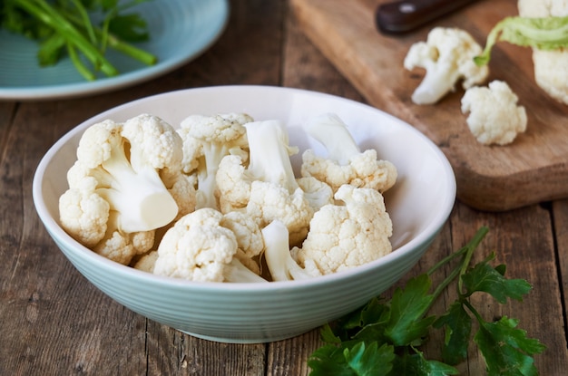 Pieces of raw cauliflower in a bowl on wooden table