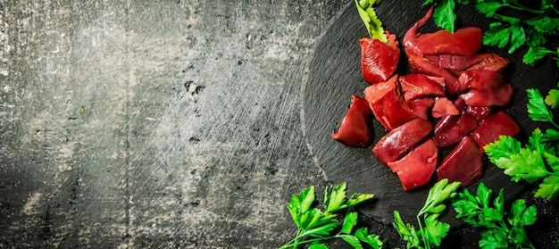 Pieces of raw liver on a stone tray with parsley