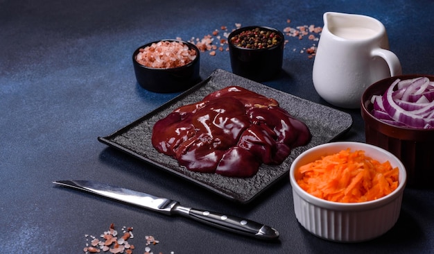 Pieces of raw liver on a wooden cutting board against a dark concrete background