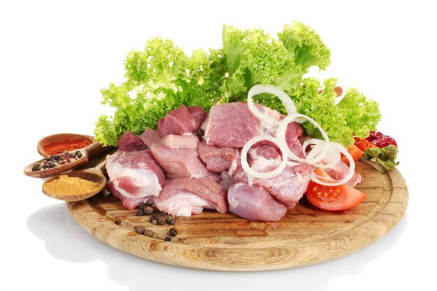 Pieces of raw meat and vegetables on wooden board isolated on white