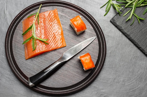 Pieces of salmon kitchen knife and sprigs of rosemary on cutting board