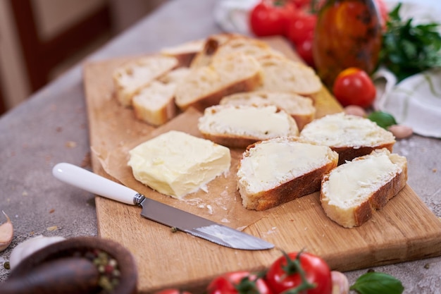 Pieces of sliced baguette with spread butter on wooden board