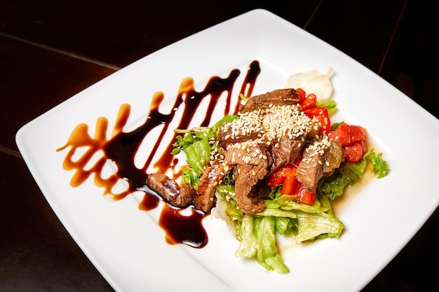 Pieces of stewed beef with red bell pepper and lettuce in a spicy sauce