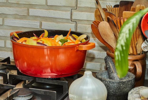 Pieces of tricolor carrots are cooked in saucepan on gas stove