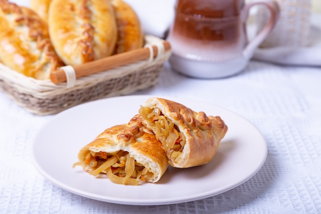 Pies (pirozhki) with cabbage. Homemade baking. Traditional Russian and Ukrainian cuisine. In the background is a basket with pies. Close-up.