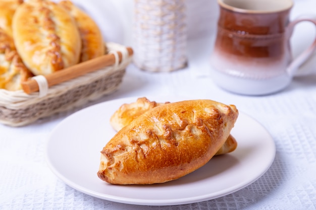 Pies (pirozhki) with cabbage. Homemade baking. Traditional Russian and Ukrainian cuisine. In the background is a basket with pies. Close-up.