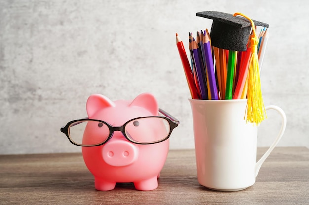 Pigging bank wearing eyeglass with coins and calculator saving bank education concept