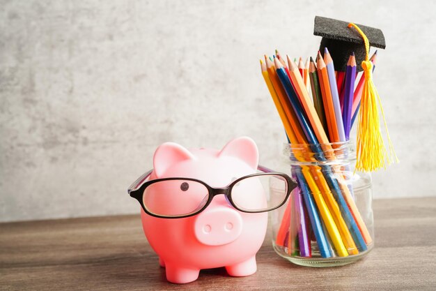 Pigging bank wearing eyeglass with coins and calculator saving bank education concept