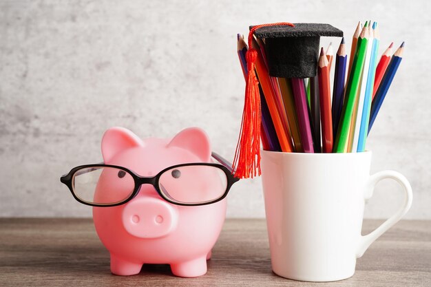 Pigging bank wearing eyeglass with coins and calculator saving bank education conceptxA