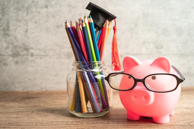 Pigging bank wearing eyeglass with colorful pencils saving bank education concept