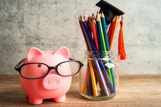 Pigging bank wearing eyeglass with colorful pencils saving bank education concept