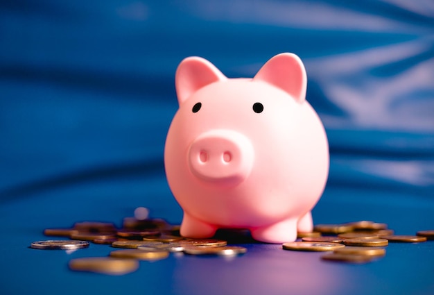 A piggy bank and coins scattered on a blue background. Finance and economics concepts