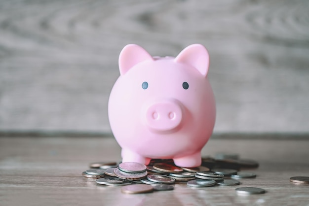 Piggy bank on coins and wooden background pink piggy bank saving money for education study or investment concept