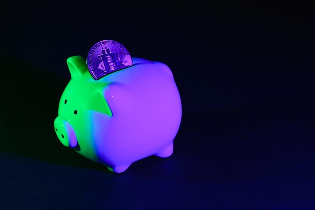 Piggy bank on a dark background with Bitcoin and greenpurple backlight Banking concept Bitcoin mining concept