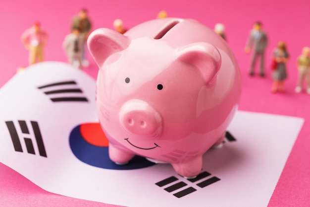 Piggy bank flag and plastic toy men concept income of the population of South Korea