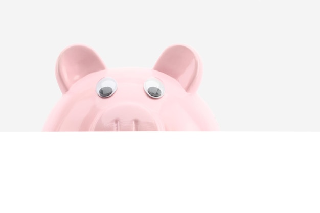 Piggy bank hiding behind a banner isolated on white