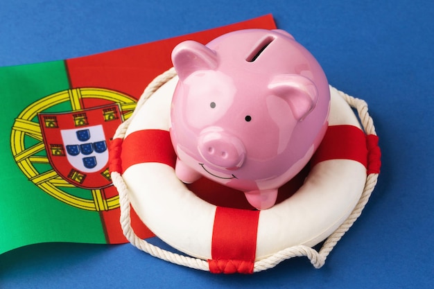 Piggy bank lifebuoy and flag on a blue background the concept of saving the Portuguese economy