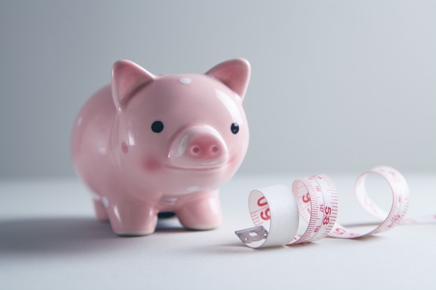 Piggy bank and measuring tape on the table