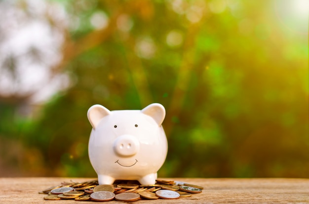 Piggy bank over pile of a golden coins on old wooden table