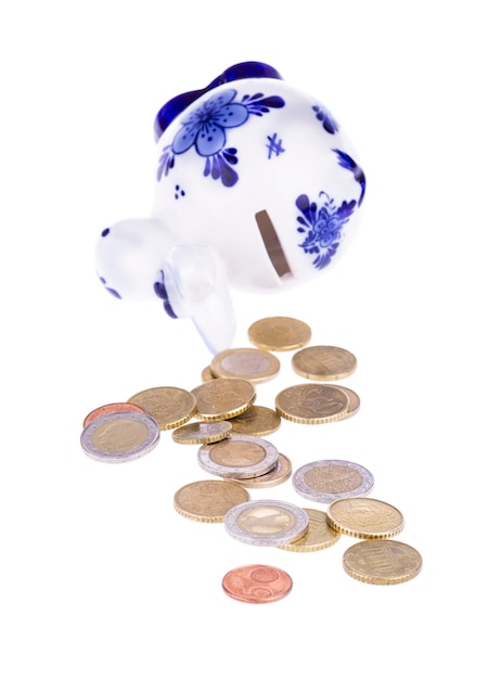 Piggy bank in a shape of a cow with blue ornament and scattered coins