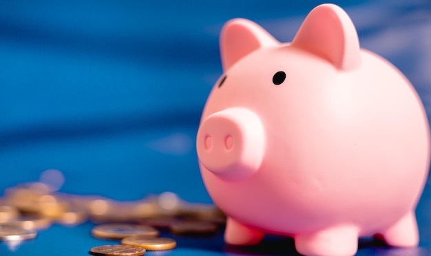 A piggy bank turned on its side and coins scattered on a blue background