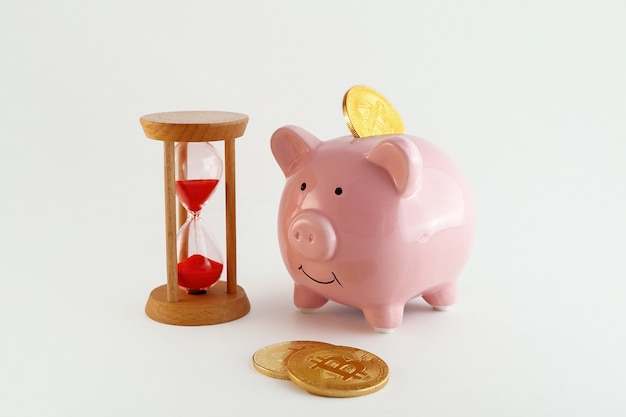 Piggy bank with bitcoin coins and hourglass  isolated