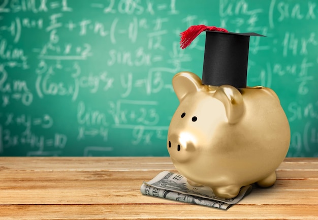 Piggy Bank with Black Graduation Hat on blackboard background