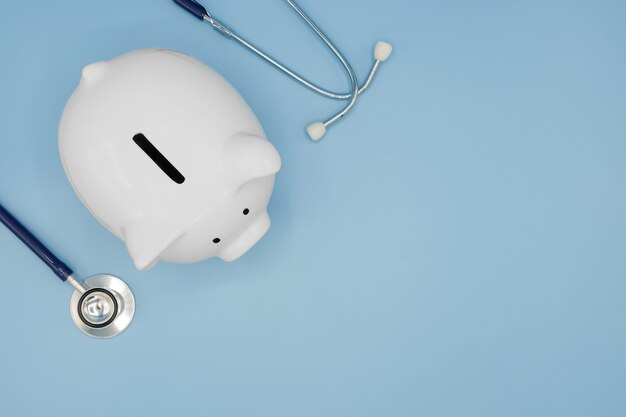 Photo piggy bank with stethoscope on blue health care financial checkup saving medical insurance concept