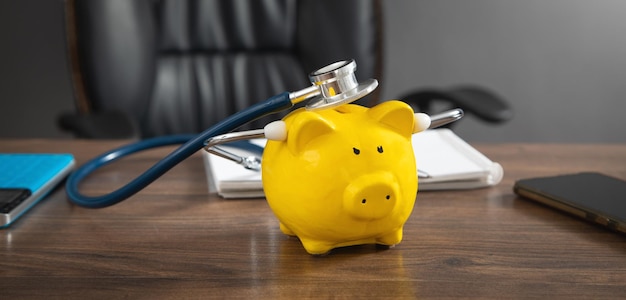 Piggy bank with stethoscope on the wooden table