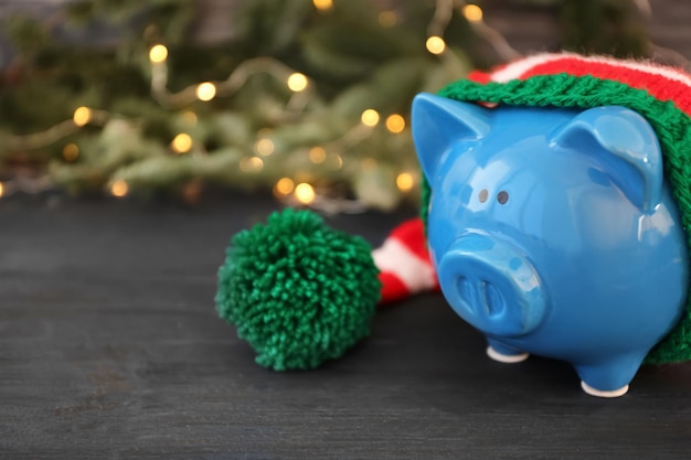 Piggy bank with striped hat and blurred Christmas lights on background