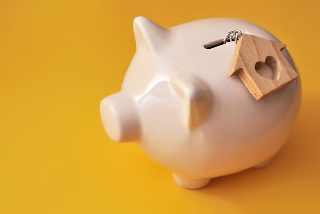 A piggy bank and a wooden house nearby a symbol of saving money for housing