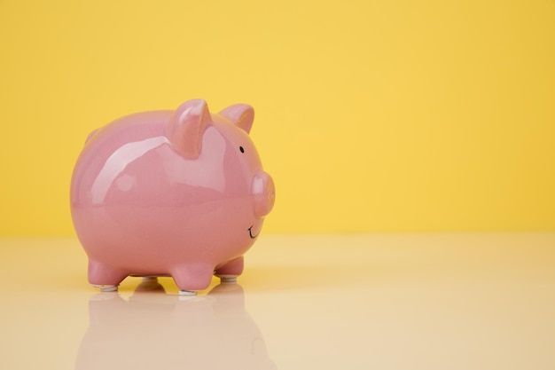 Piggy bank on yellow background looks to right space for text Finance saving money