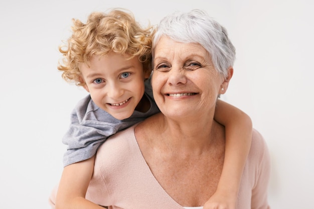 Piggyback portrait and grandmother with child embrace happy and bonding against a wall background Love face and senior woman with grandchild having fun hug and enjoying the weekend together