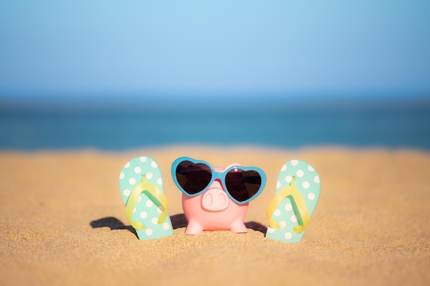 Piggybank on the beach against sea and sky background Savings for summer travel and vacation concept