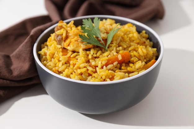 Pilaf in bowl and towel on white background close up