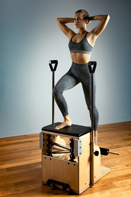 Pilates reformer chair woman fitness yoga gym exercise. Correction of musculoskeletal system, beautiful body. Correct posture.