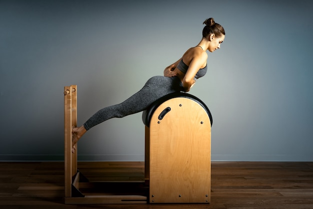 Pilates trainer exercises on a pilates barrel. Body training, perfect body shape and posture correction opporno motor apparatus. Copy space. woman doing exercises on ladder barrel.