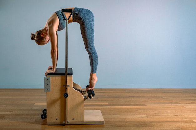 Pilates woman in a Cadillac reformer doing stretching exercises in the gym