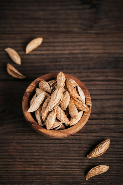 Pile of Almond nuts in a bowl on a dark wooden background. Fresh nuts in their shells.