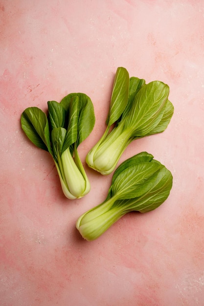 A pile of baby bok choy on a pink background